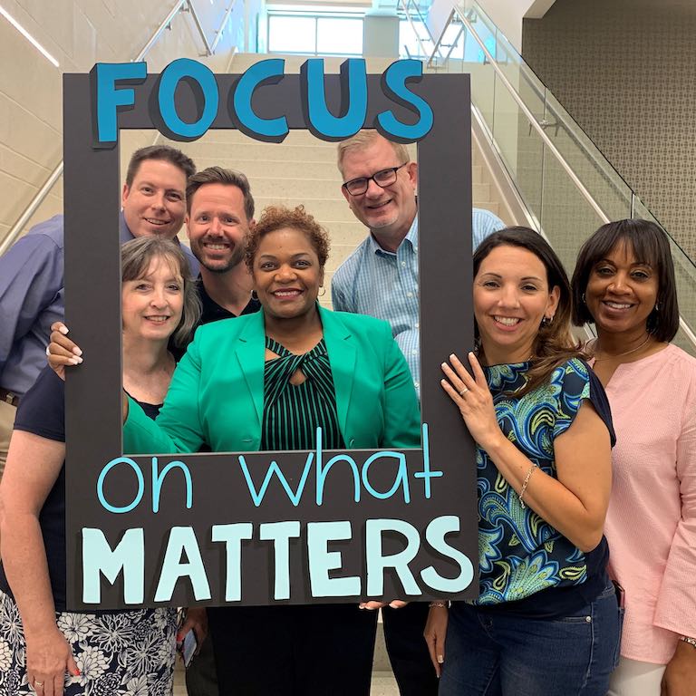 A. Tracie Brown and Steven Wurtz of Arlington ISD are photographed with colleagues holding a sign that reads "focus on what matters".