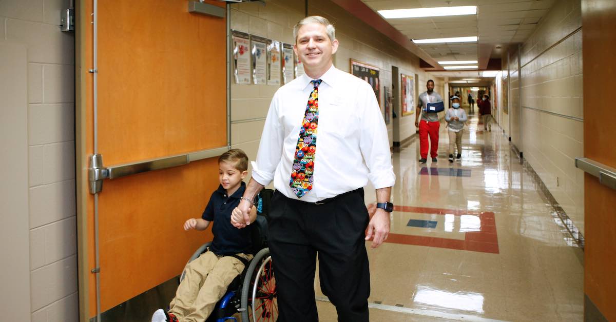 Principal Josh Leonard escorts a student in a wheelchair through the halls of Blanton Elementary school in Arlington ISD.