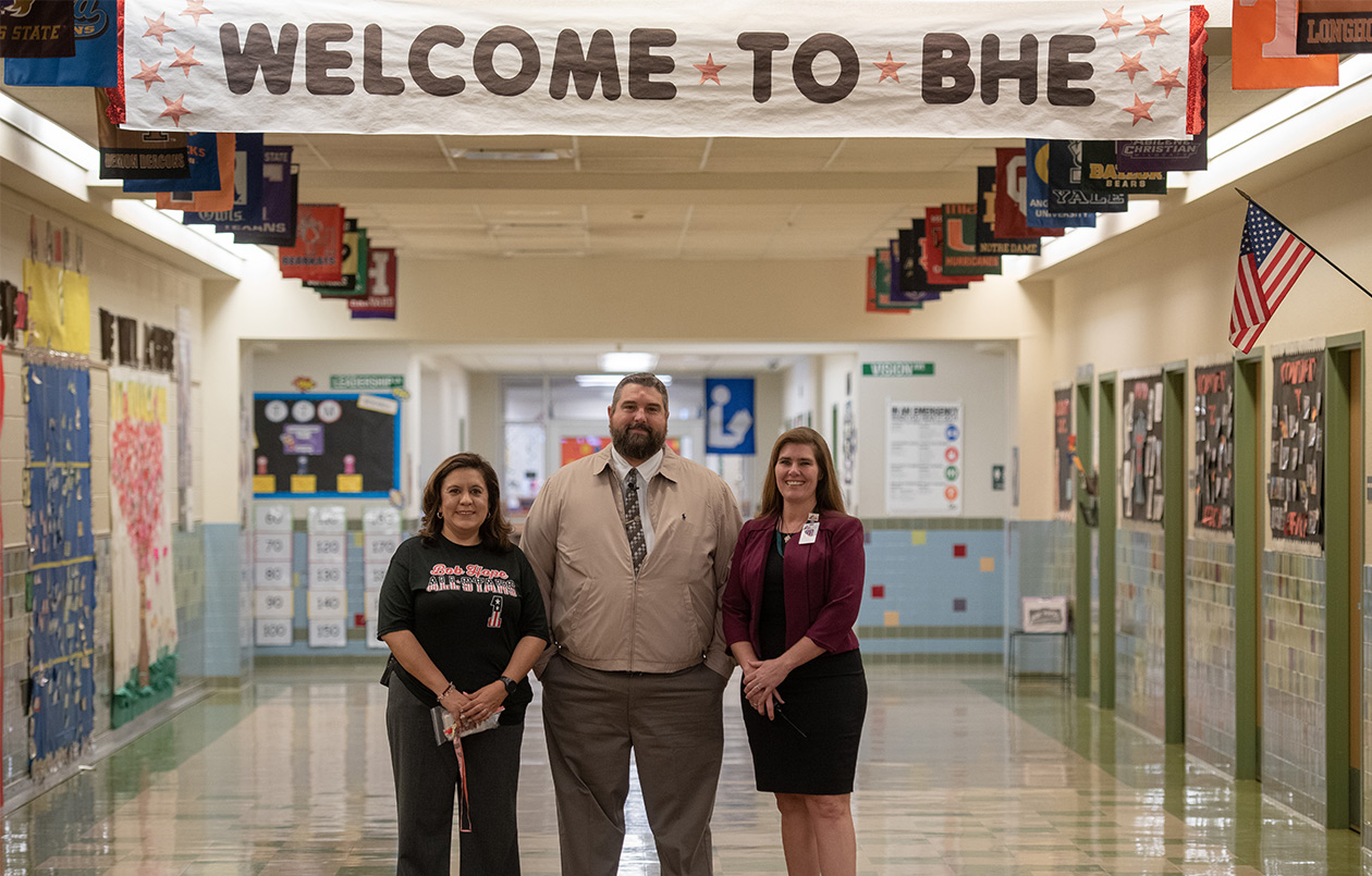 District leaders posing for a photo in a campus hallway.