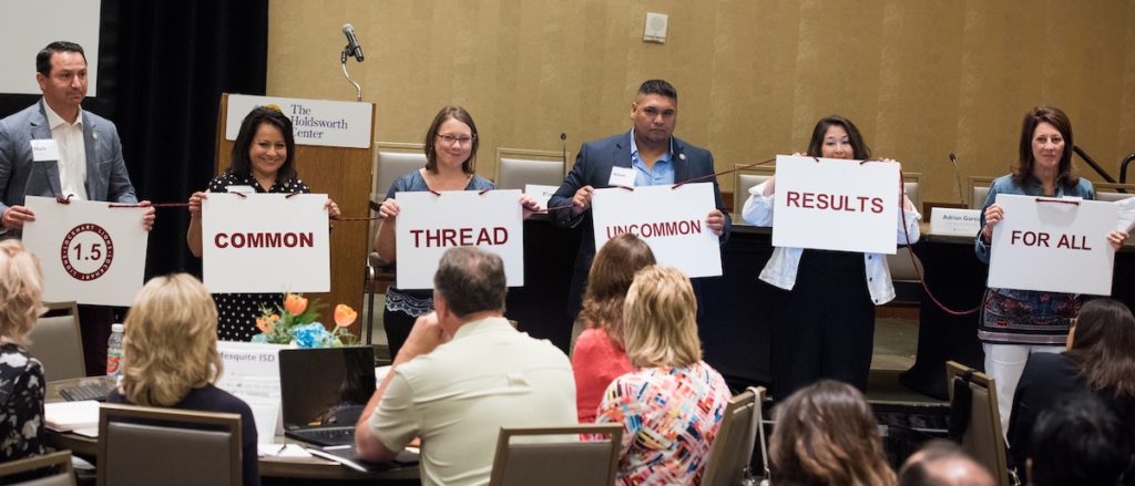 Adam Galvan (third from the right) holds up a sign with his team during a learning session at Holdsworth’s two-year District Leadership Program.