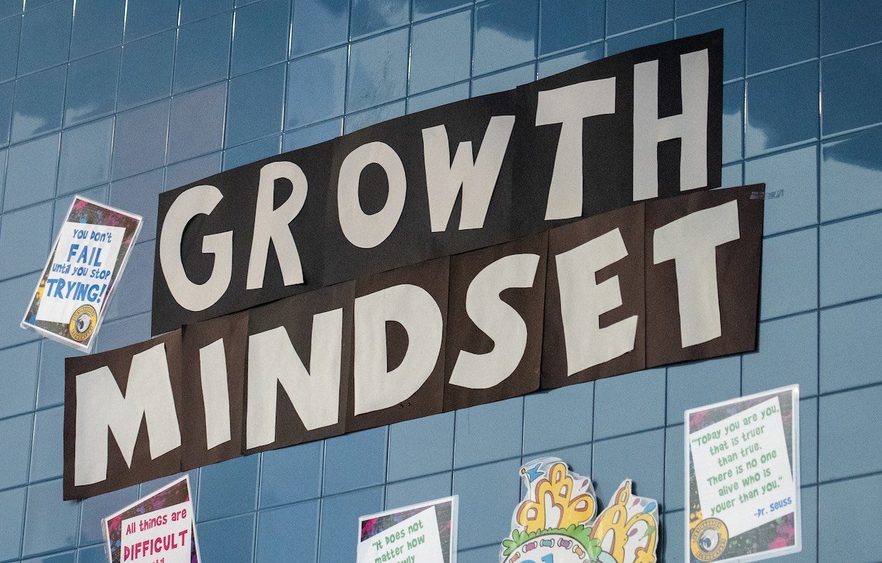 A photo of a wall collage that spells Growth Mindset in large white letters on a blue tile wall.