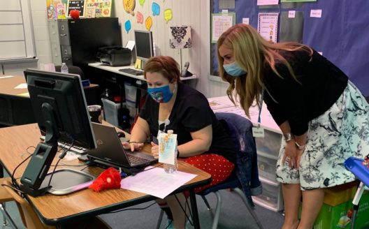 Klein ISD superintendent, Jenny McGown, looks over the shoulder of a colleague at a computer.