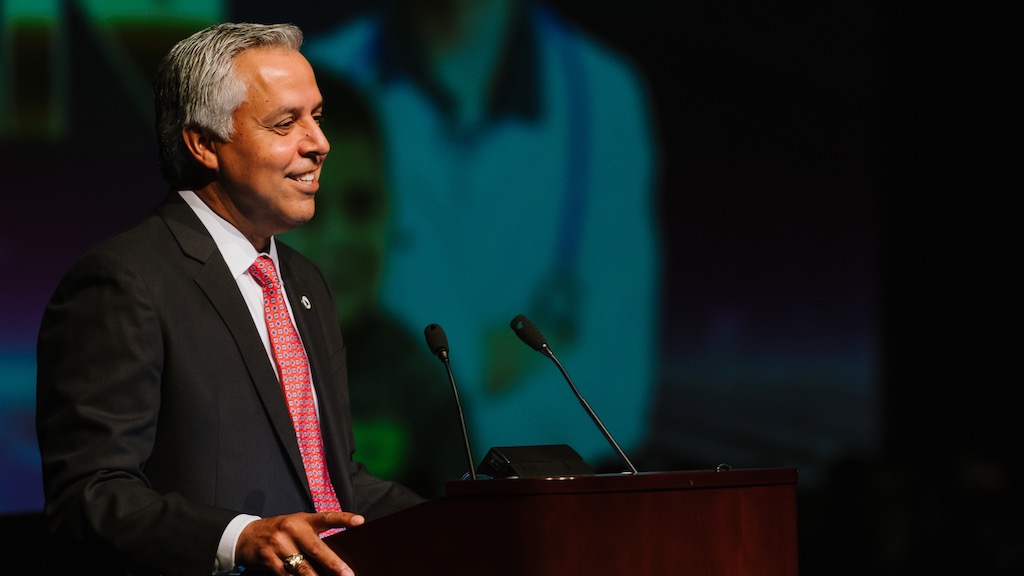 Dr. Art Cavazos, superintendent of Harlingen CISD in the Rio Grande Valley, is pictured speaking at a podium.