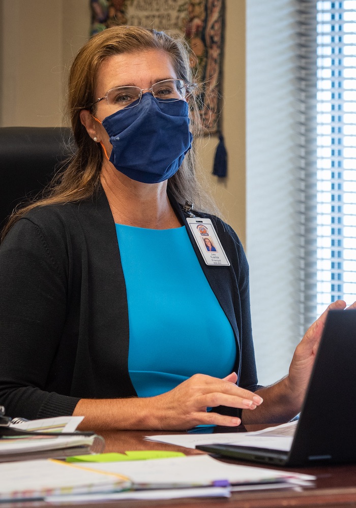 Amy Garza, a principal at Medio Creek Elementary in Southwest ISD in San Antonio, is photographed at her desk on campus wearing a face mask.