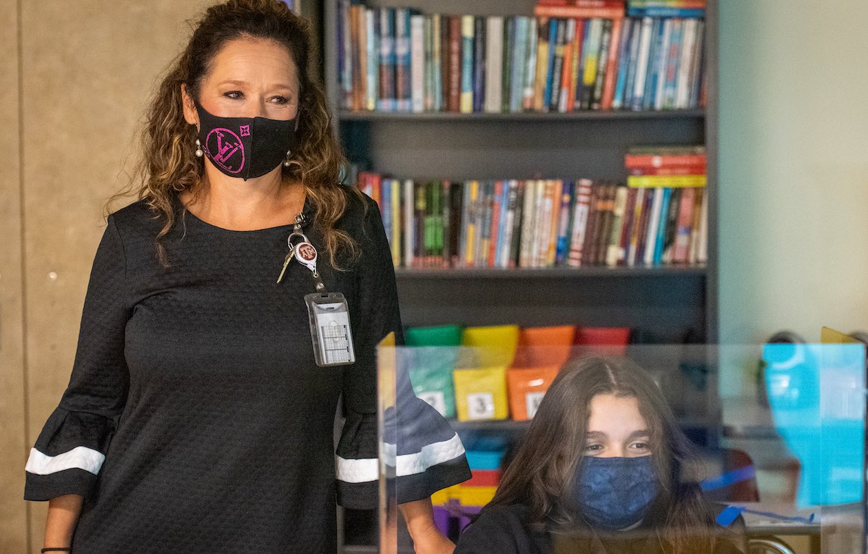 Anitra Crisp, a principal at McNair Middle School in Southwest ISD, is photographed in a campus classroom with a student, both of whom are wearing face masks.