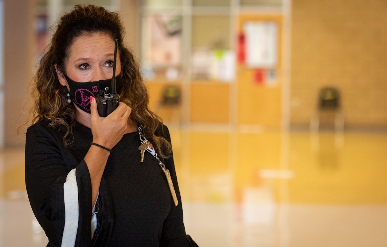 Anitra Crisp, a principal at McNair Middle School in Southwest ISD, is photographed on campus wearing a face mask and talking on a two-way radio.