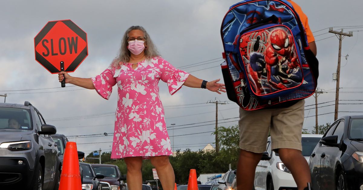 Michelle La Rue, principal of Rolling Meadows Elementary in Judson ISD, is photographed stopping traffic so that a student can cross on the first day of school on August 16, 2021.